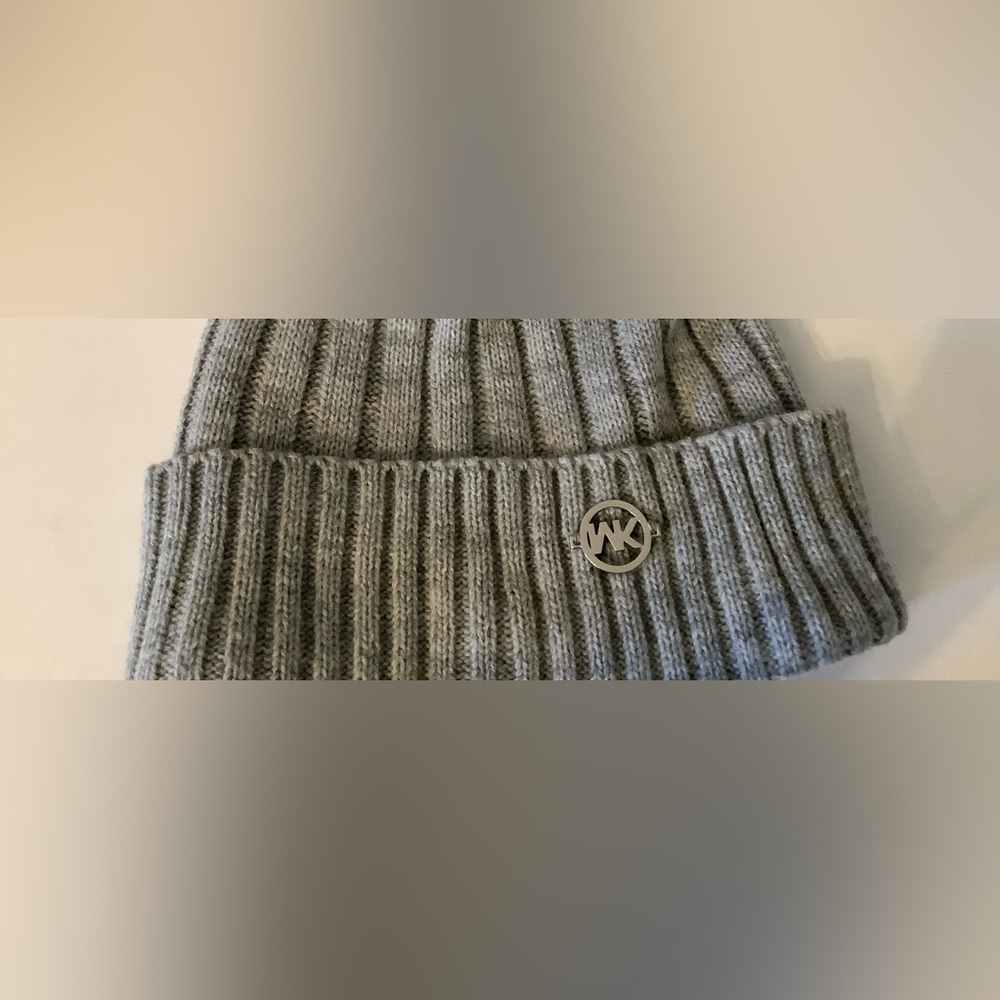 Micheal kors hat grey and has a gold label at the end.